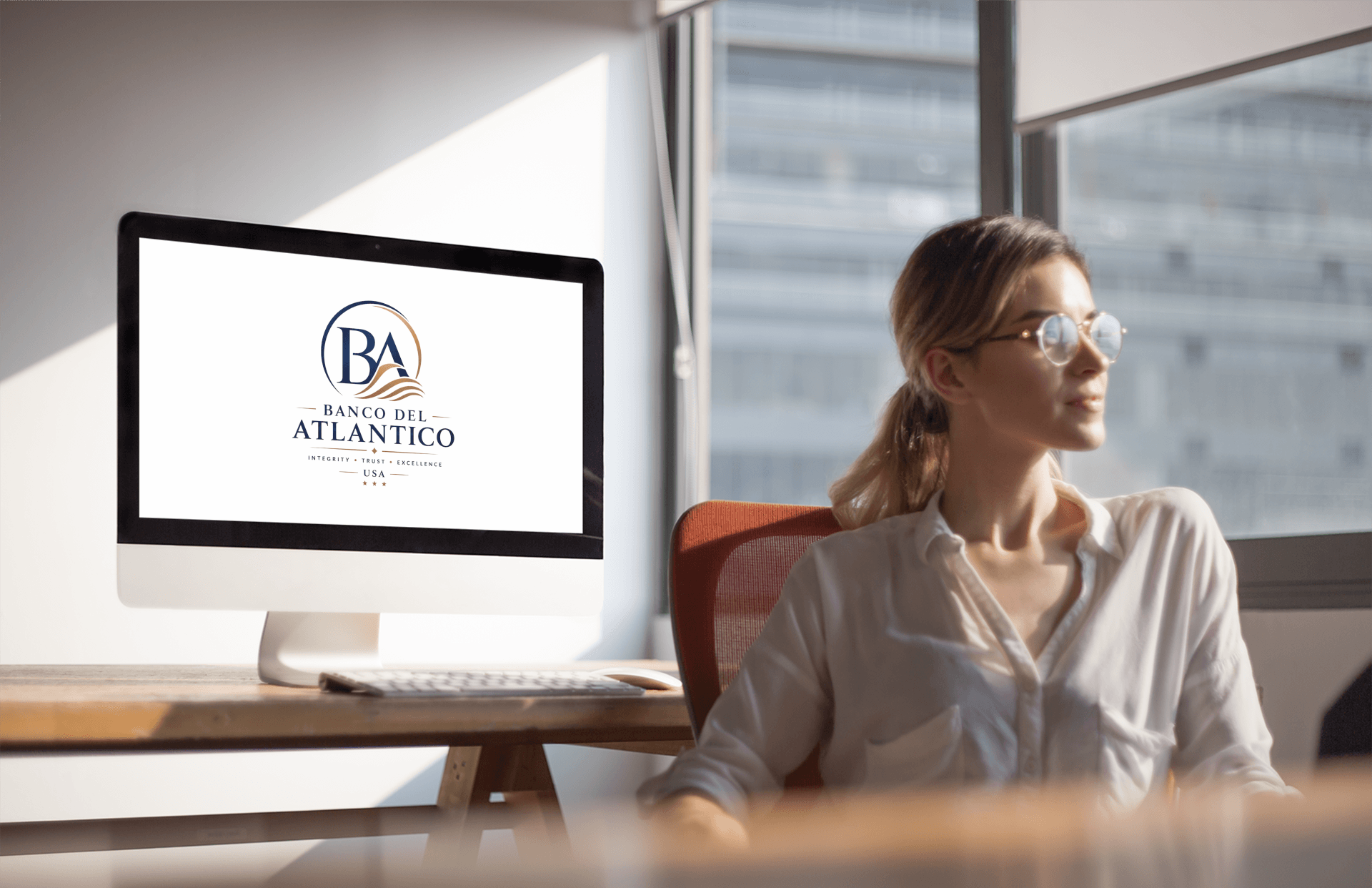 Banco Del Atlantico brand mark on an office screen beside a professional at her desk